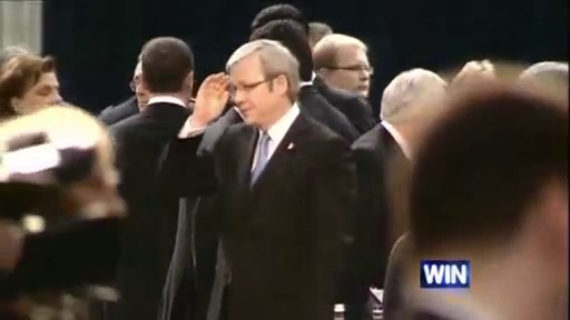 Kevin Rudd salutes in a crowd of people inside