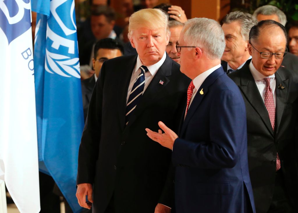 Donald Trump and Malcolm Turnbull stand and talk. There are other people behind them