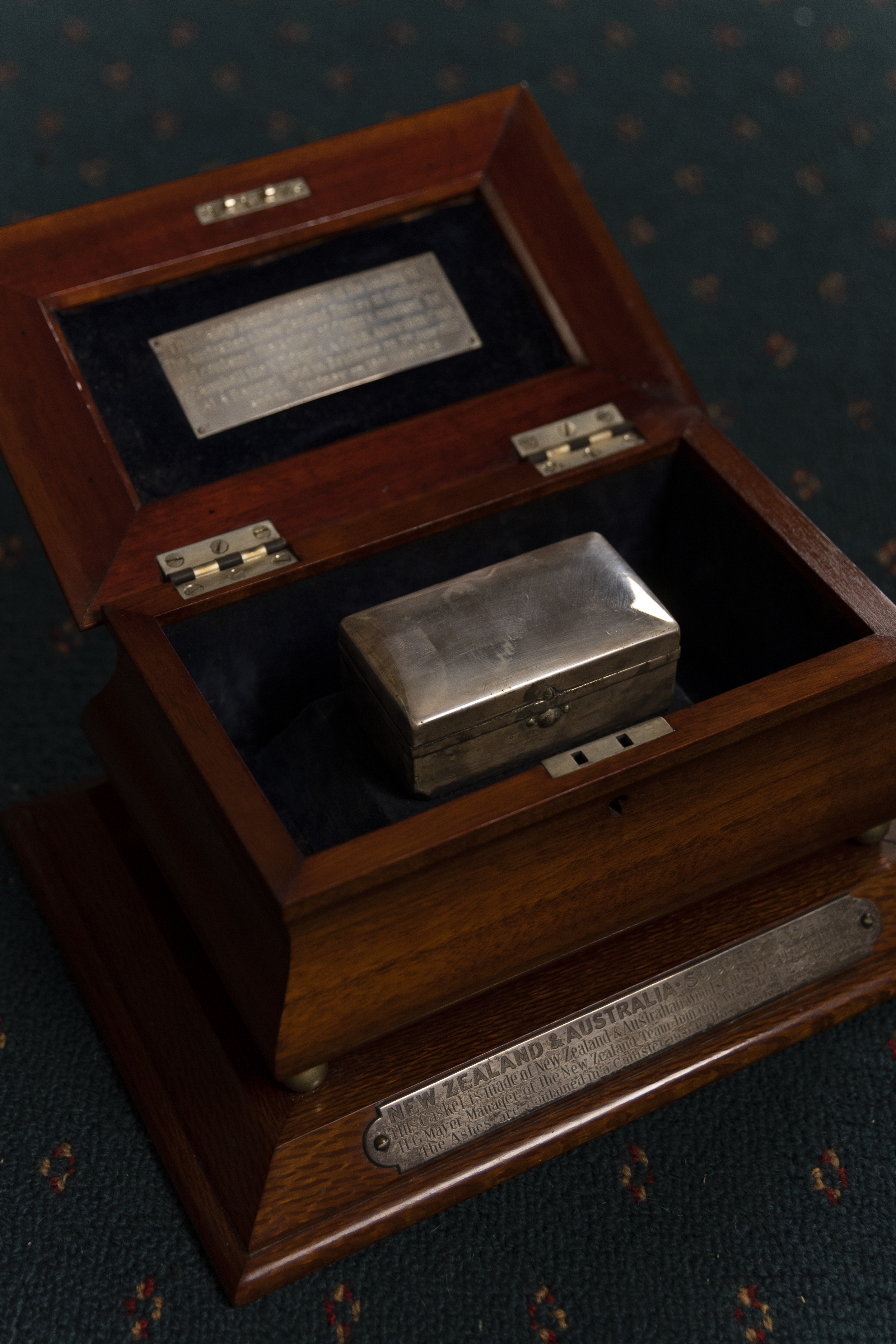 An opened wooden box with a smaller metal box inside it