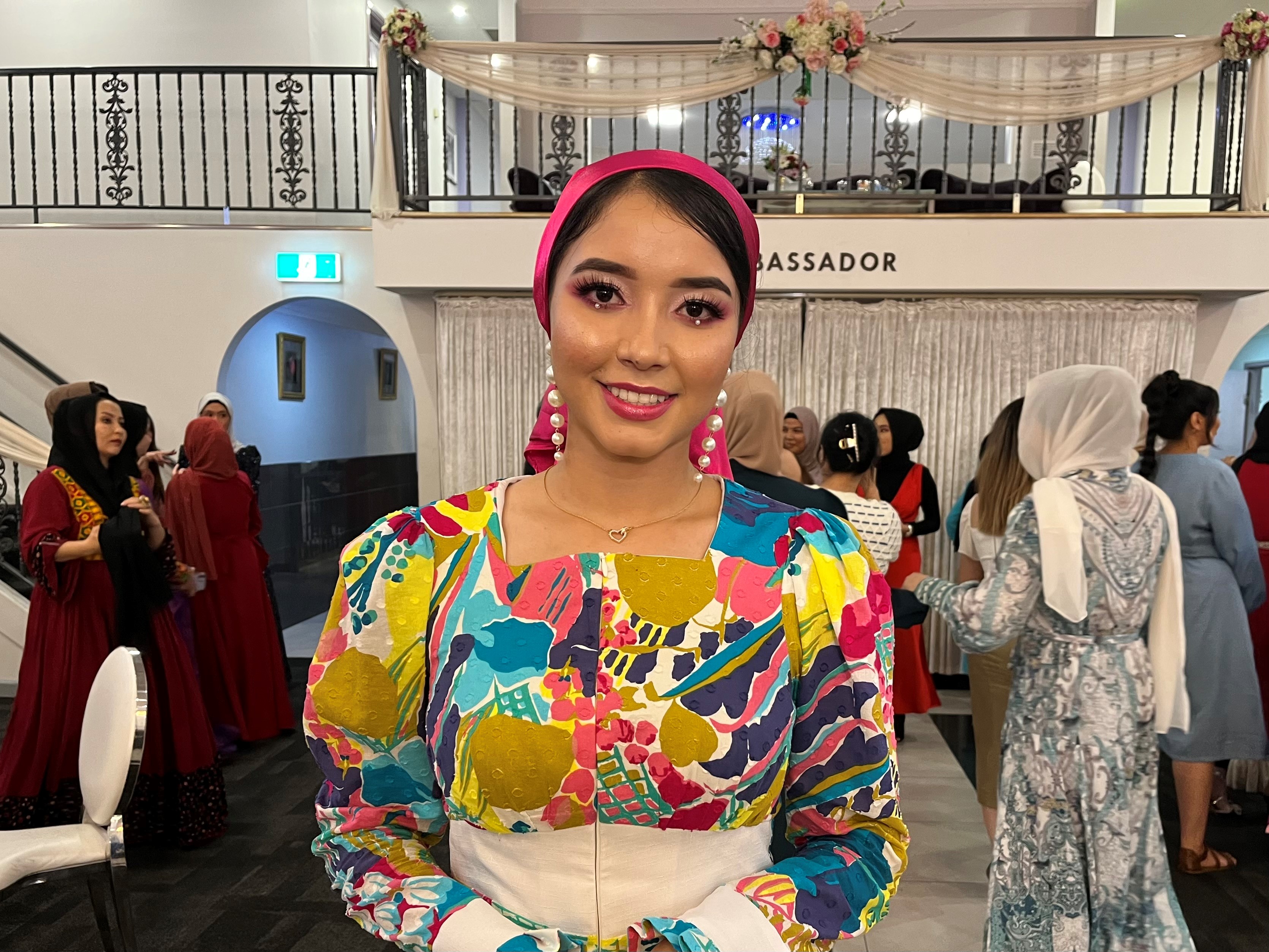 Model Nilofar Sadeqi in a beautiful colourfully printed jumpsuit and glamorous makeup smiling at the camera