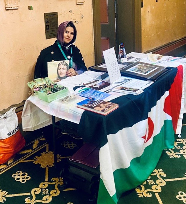 A woman sitting at a desk draped in a flag