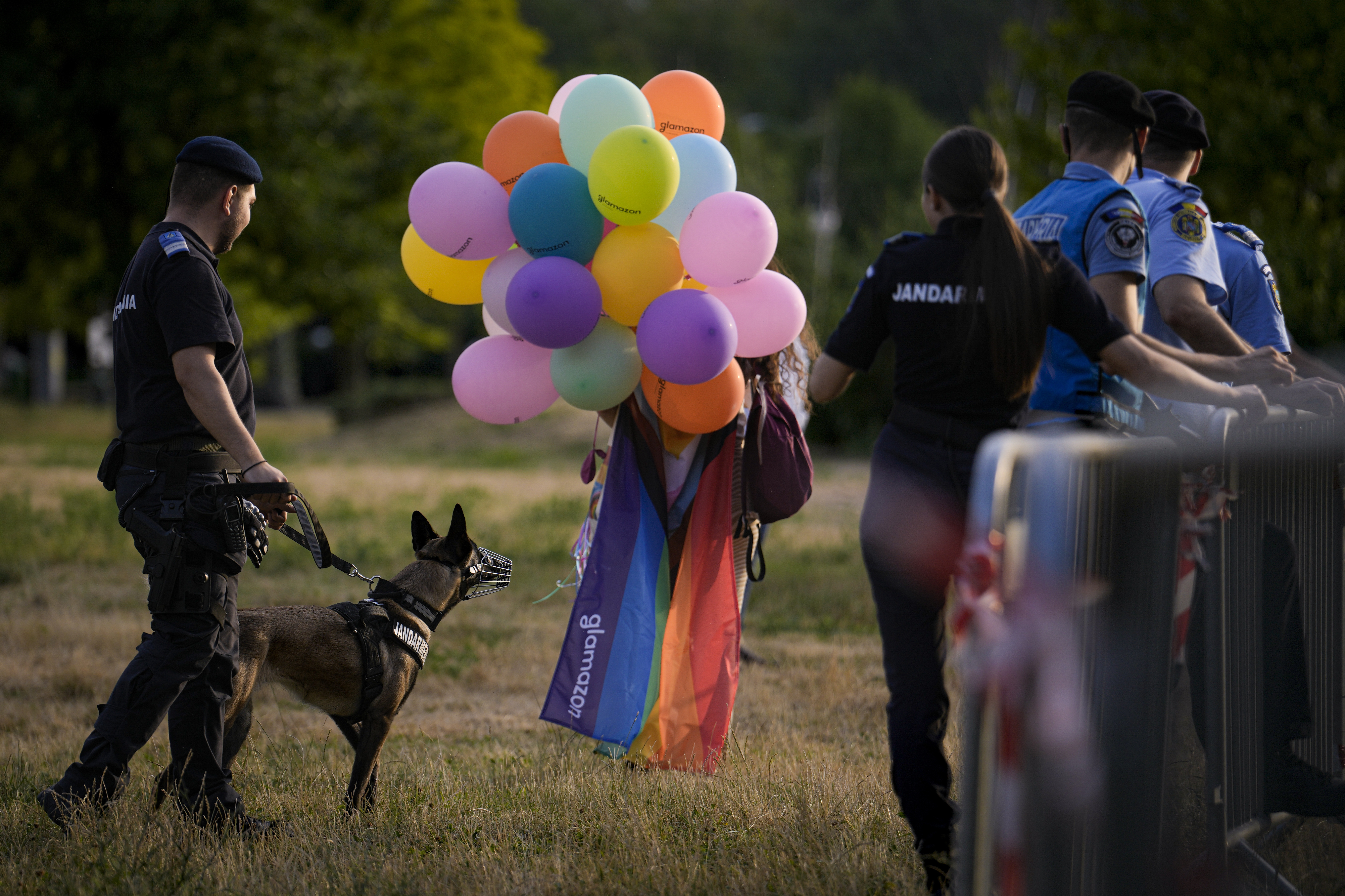 A woman holding a bunch of coloured balloons walks between Romanian riot police officers after the gay pride parade in Bucharest, Romania