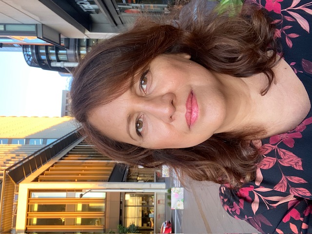 A self-portrait of a woman in the street looking at the camera with a serious expression.