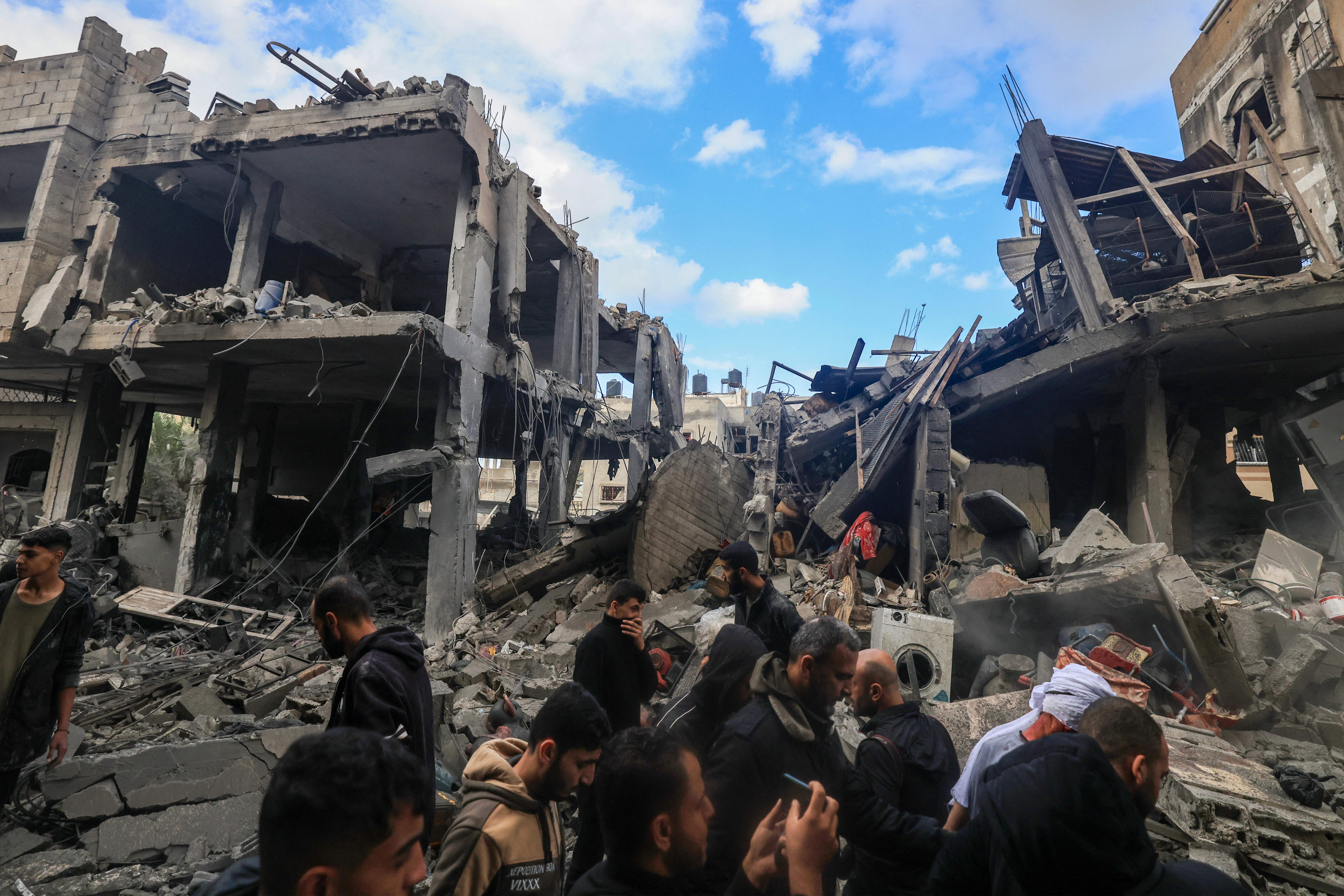 People walking amid the rubble of destroyed buildings.