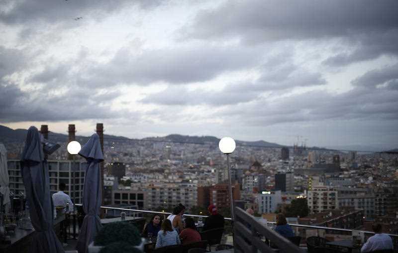 People gather in a bar with the skyline of Barcelona in the background during the Catalan National Day in Barcelona, Spain, Monday, Sept. 11, 2017.