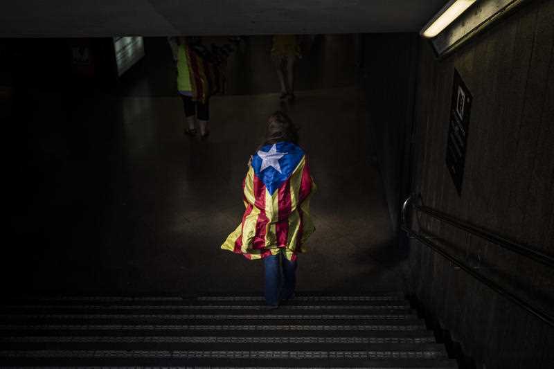 A woman enters in a Barcelona's metro station wrapped with an "estelada" or independence flag, during the Catalan National Day in Barcelona, Spain, on Monday, Sept. 11, 2017.