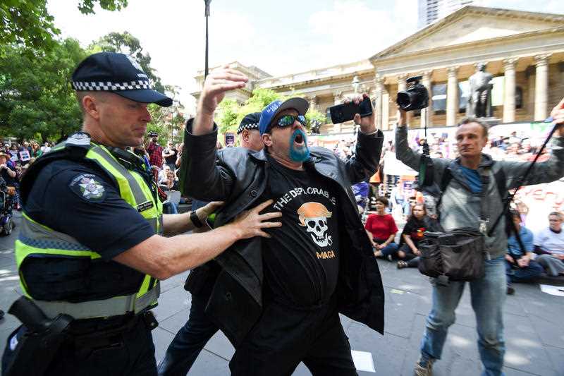 A man wearing a 'Make Australia Great Again' cap tries to disrupt speeches during a refugee rally in Melbourne. 