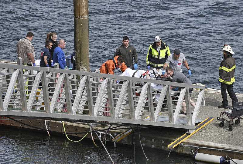 Emergency response crews transport an injured passenger to an ambulance after a small aircraft collided midair. 