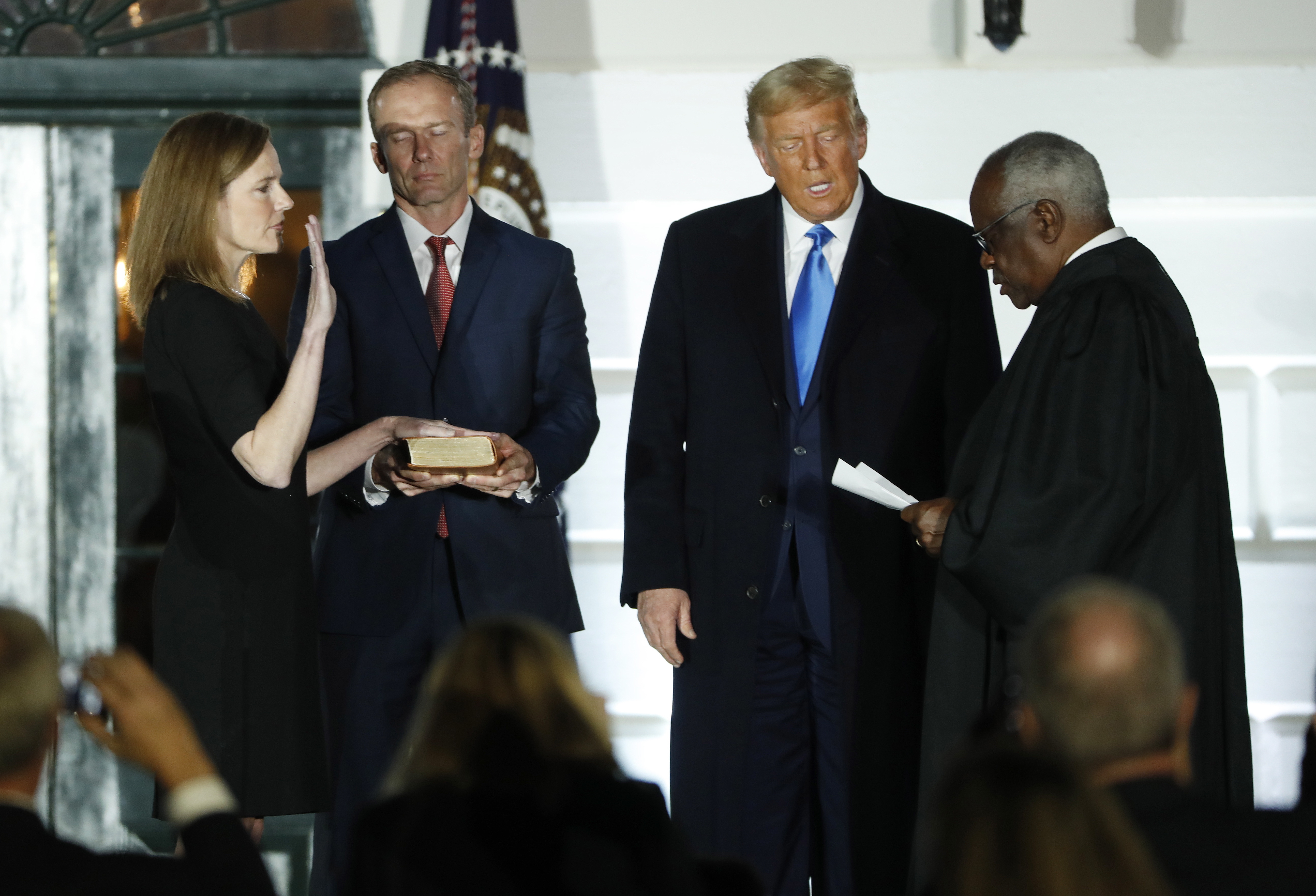 US President Donald Trump stands with US Supreme Court Justice Clarence Thomas (R) as he swears in Judge Amy Coney Barrett (L). 