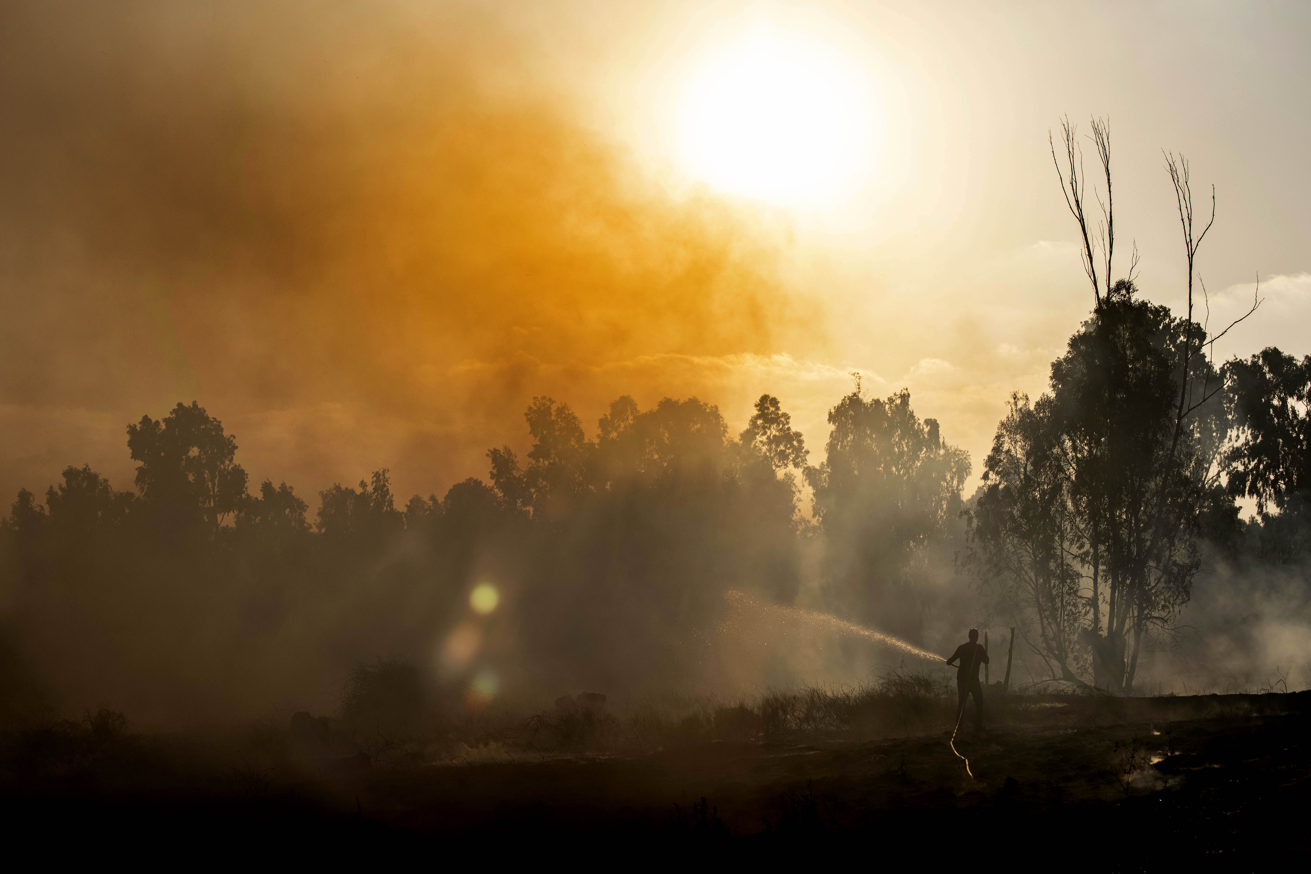 A man works at the site of a fire on the Israeli side of the border between Israel and Gaza