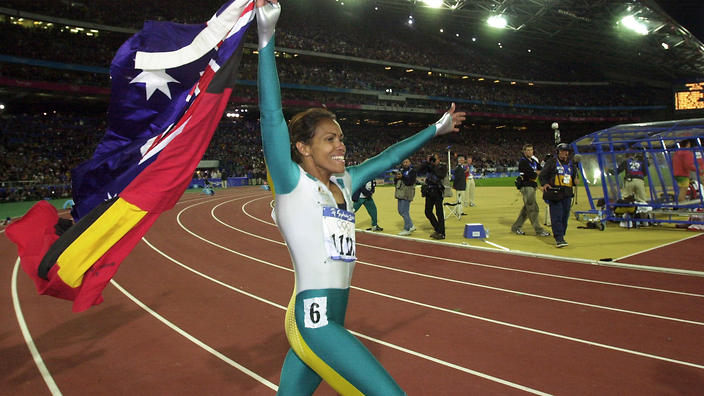 Cathy Freeman walks a lap of honour, carrying the Australian and Aboriginal Flags, after winning Gold in the Women's 400m Finals at the 2000 Sydney Olympics