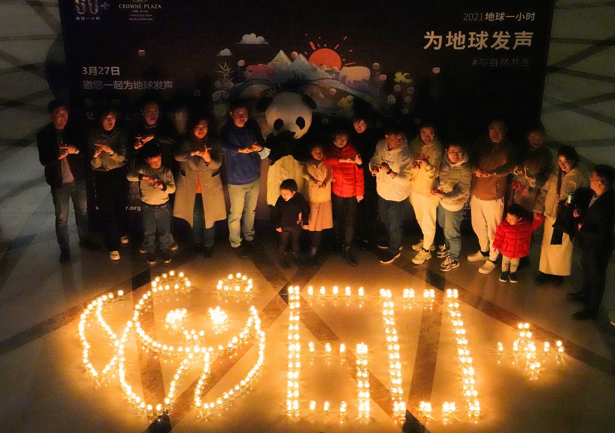 Guests at Crowne Plaza Nanshan hotel pose for a photo as part of an Earth Hour event in Yantai, east China's Shandong Province.