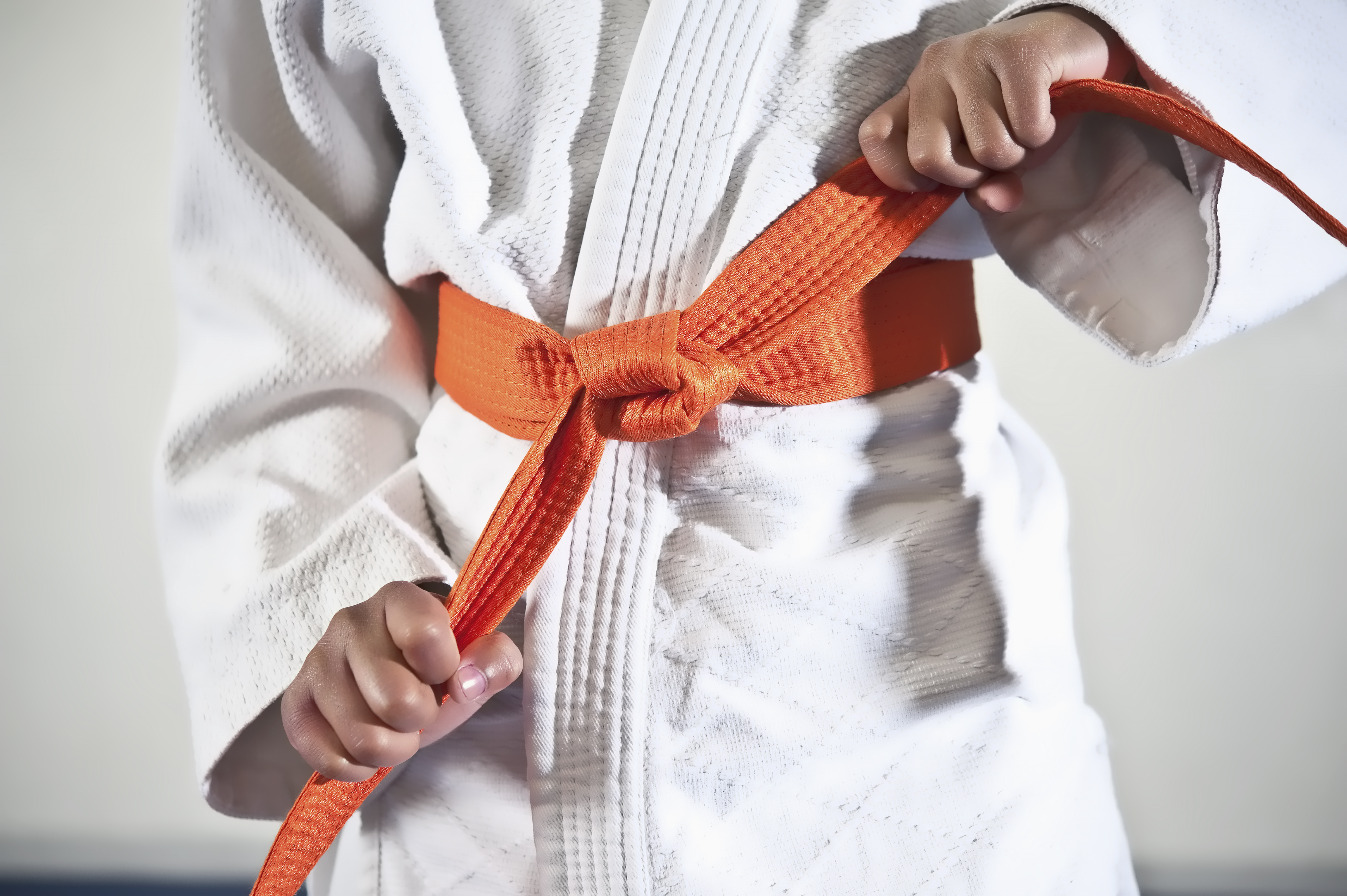 African American boy tightening karate belt