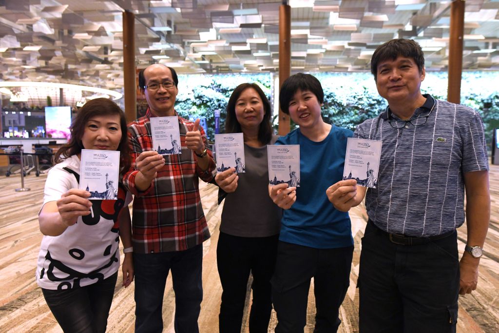 Passengers of flight SQ22, Singapore Airlines' inaugural non-stop flight to New York pose with souvenir cards after their their check-in at Changi.