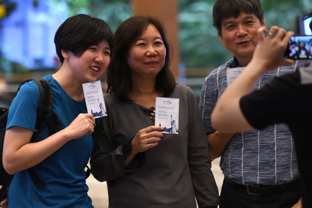 Passengers of flight SQ22, Singapore Airlines' inaugural non-stop flight to New York pose with souvenir cards.