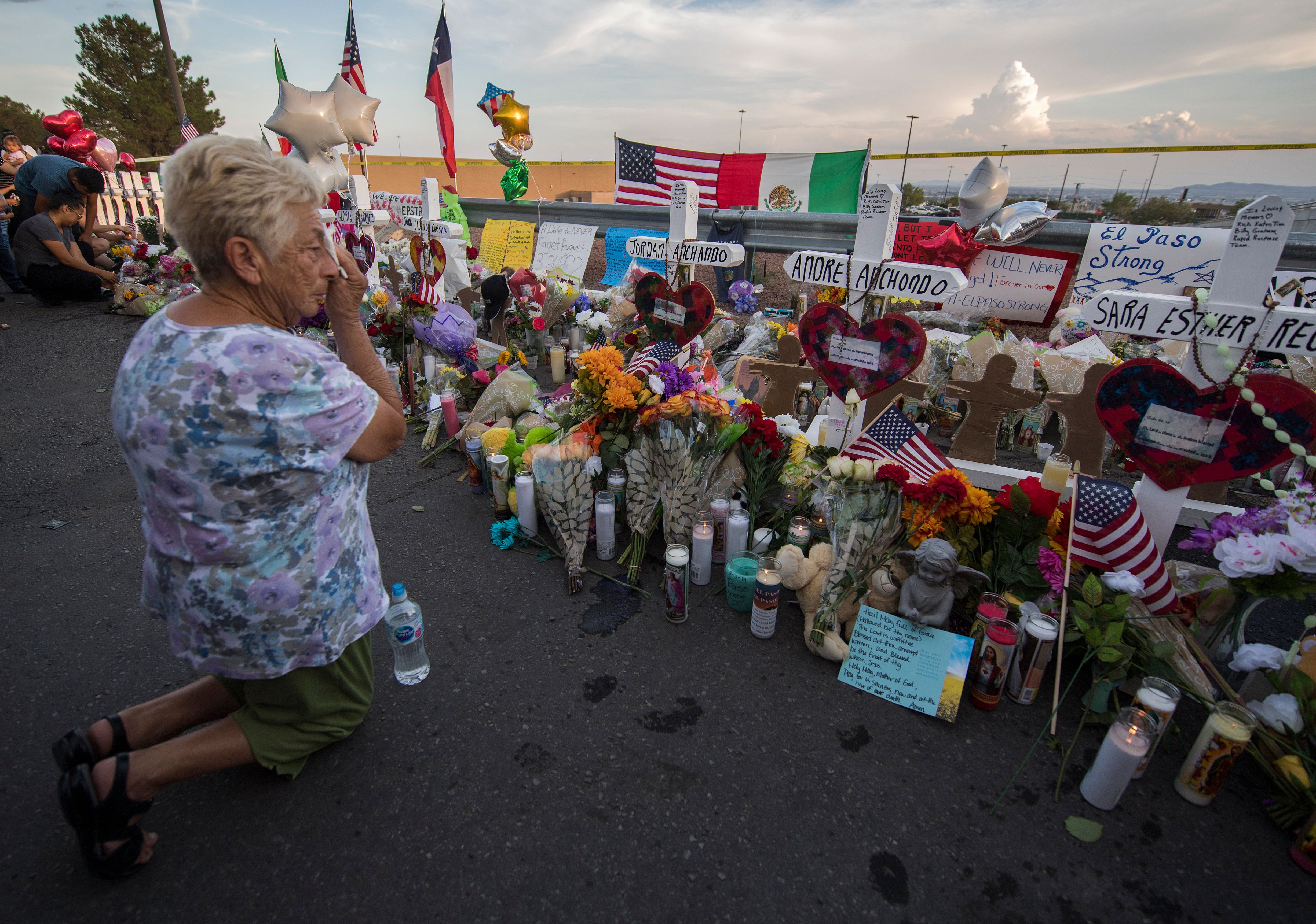 A woman prays at a makeshift memorial for victims of the Walmart shooting.