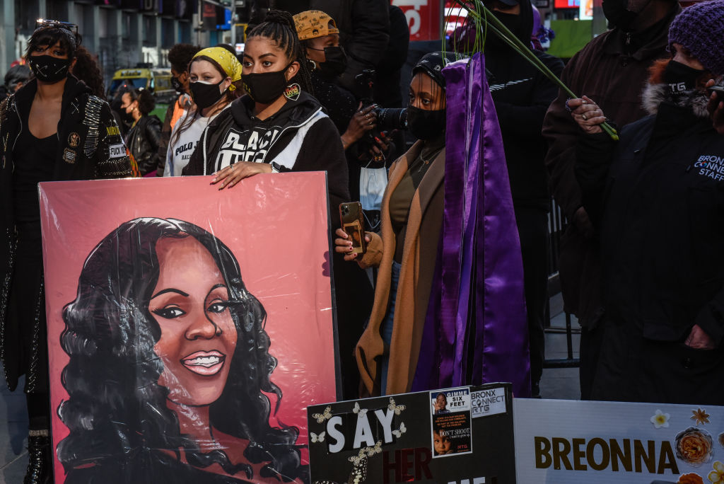 A person holds a placard with Breonna Taylor's face during a protest in New York City to mark the one year anniversary of her death.