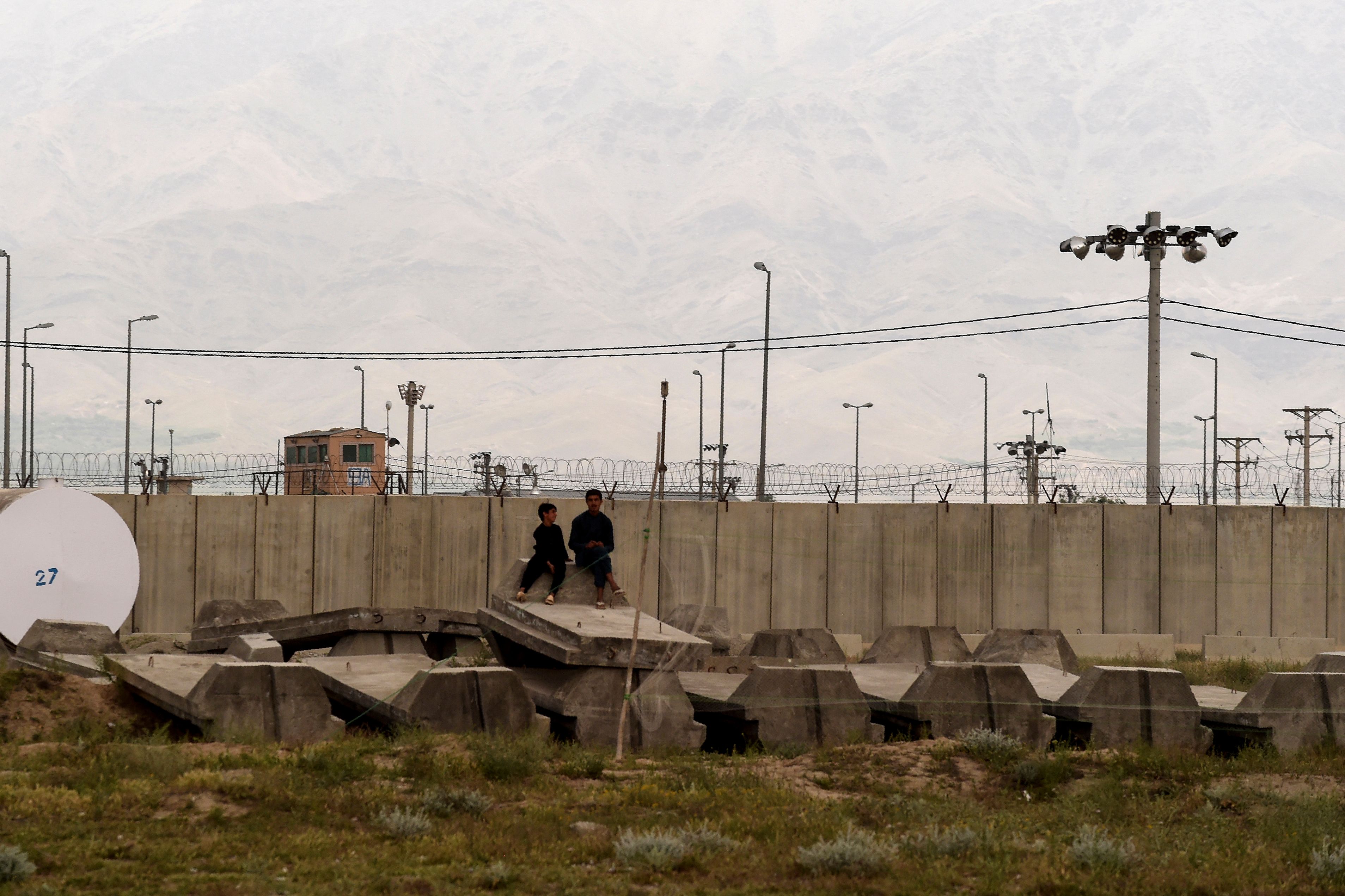 Children sit outside a US military base in Bagram, some 50 km north of Kabul on 29 April, 2021.