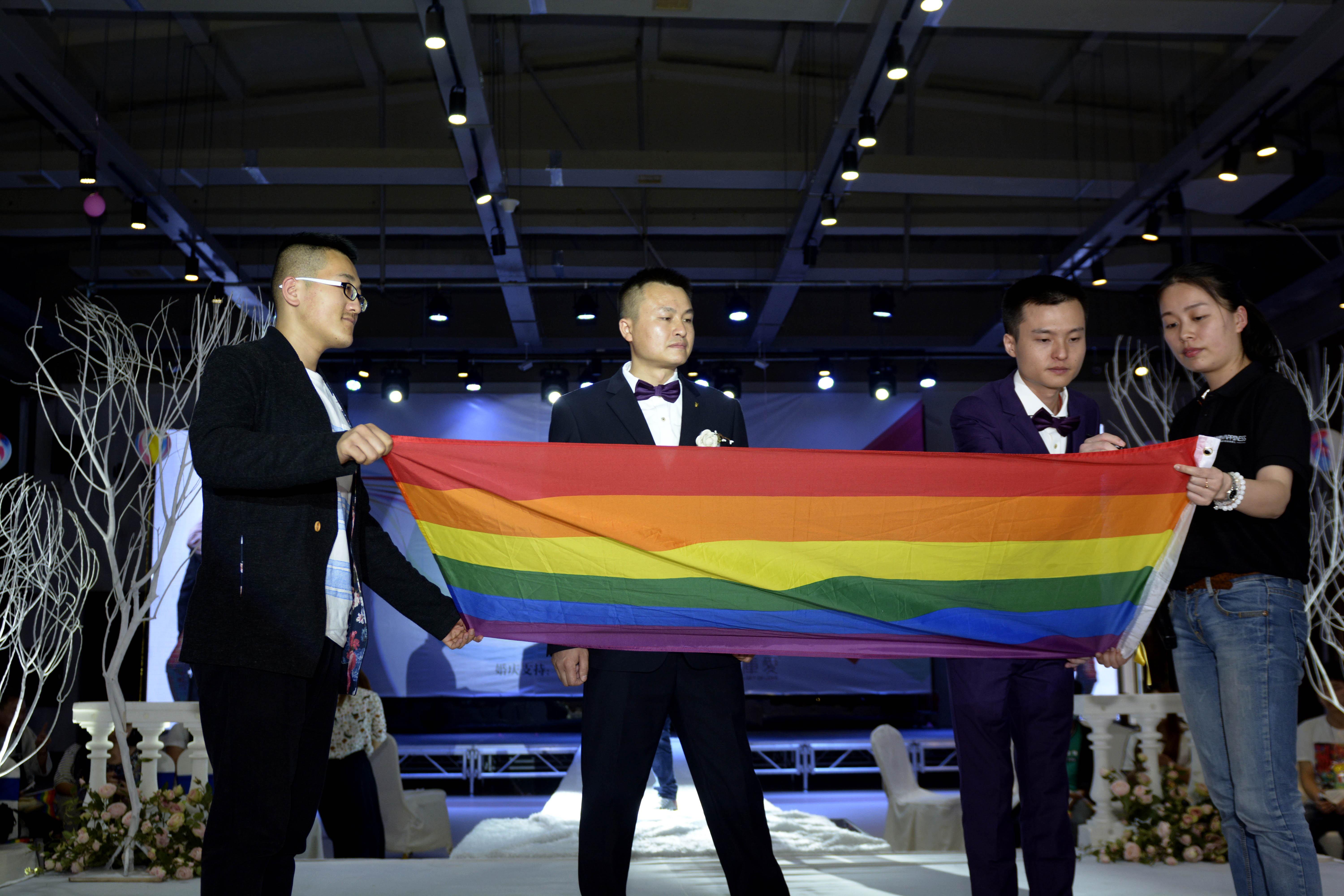 Hu Mingliang and his partner Sun Wenlin sign on a rainbow flag during their legally unrecognised wedding ceremony in central China.