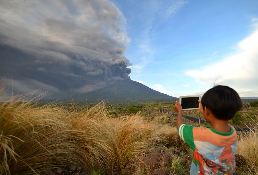 A boy takes pictures during Mount Agung's eruption seen from Kubu sub-district in Karangasem Regency on Indonesia's resort island of Bali on November 26, 2017.