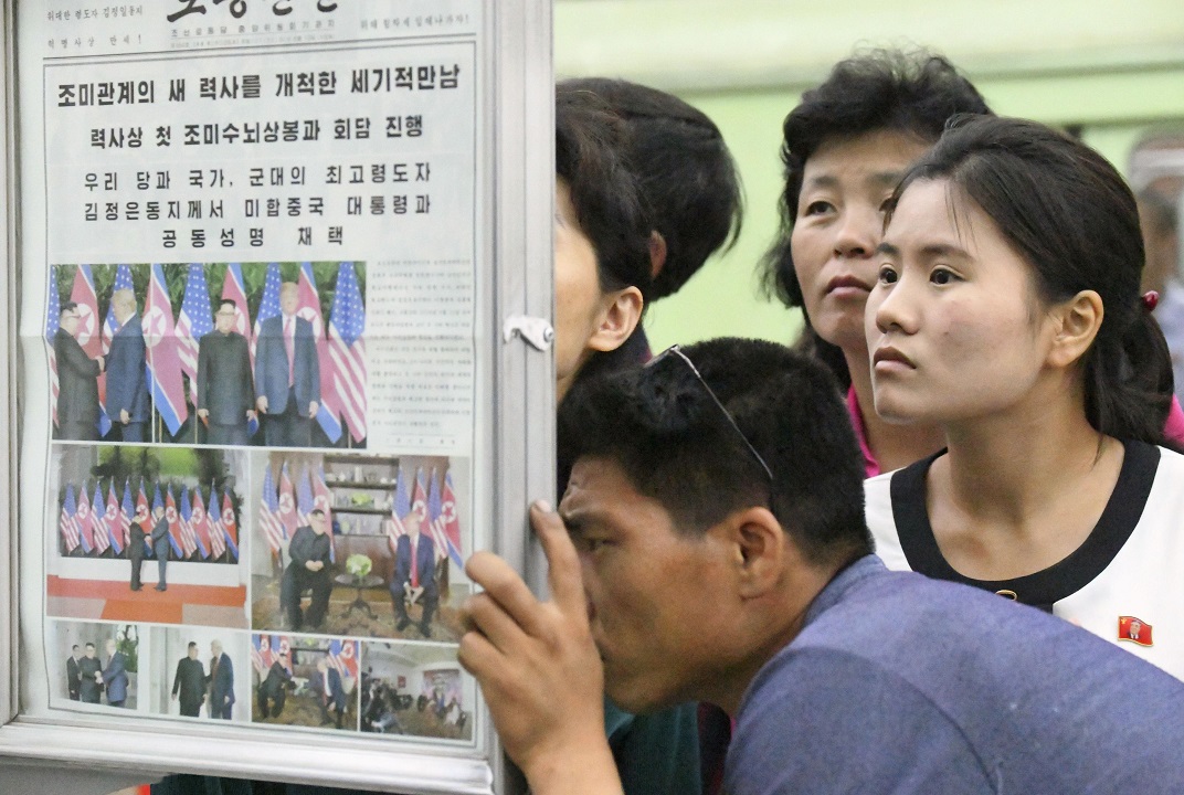 People gather to read the official newspaper of North Korea's ruling Workers' Party at a subway station in Pyongyang.