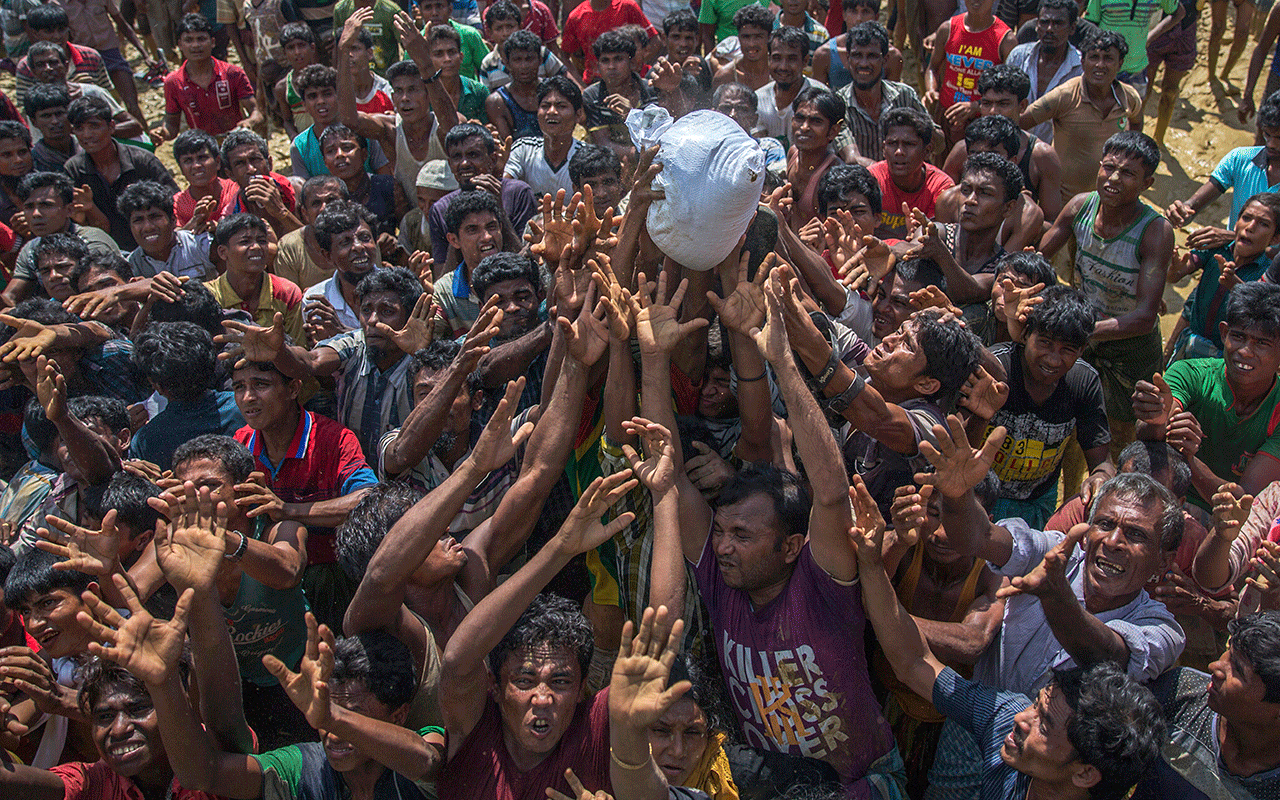 Rohingya Muslims, who crossed from Myanmar into Bangladesh, stretch their arms to catch a bag of rice thrown at them during distribution of aid In September.