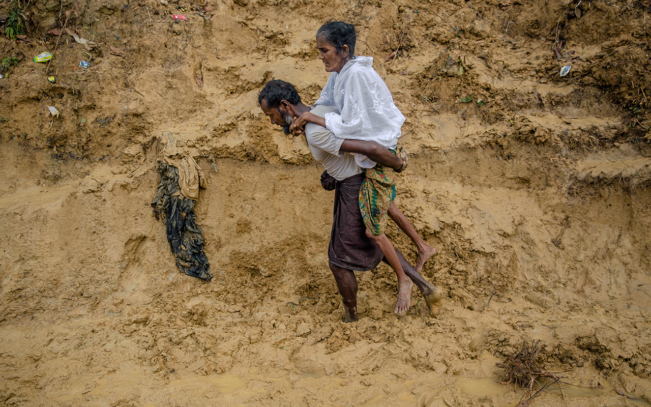 Alishaan, a Rohingya Muslim man, carries his sick mother Aishya Khatoon to a hospital at Taiy Khali refugee camp, Bangladesh.