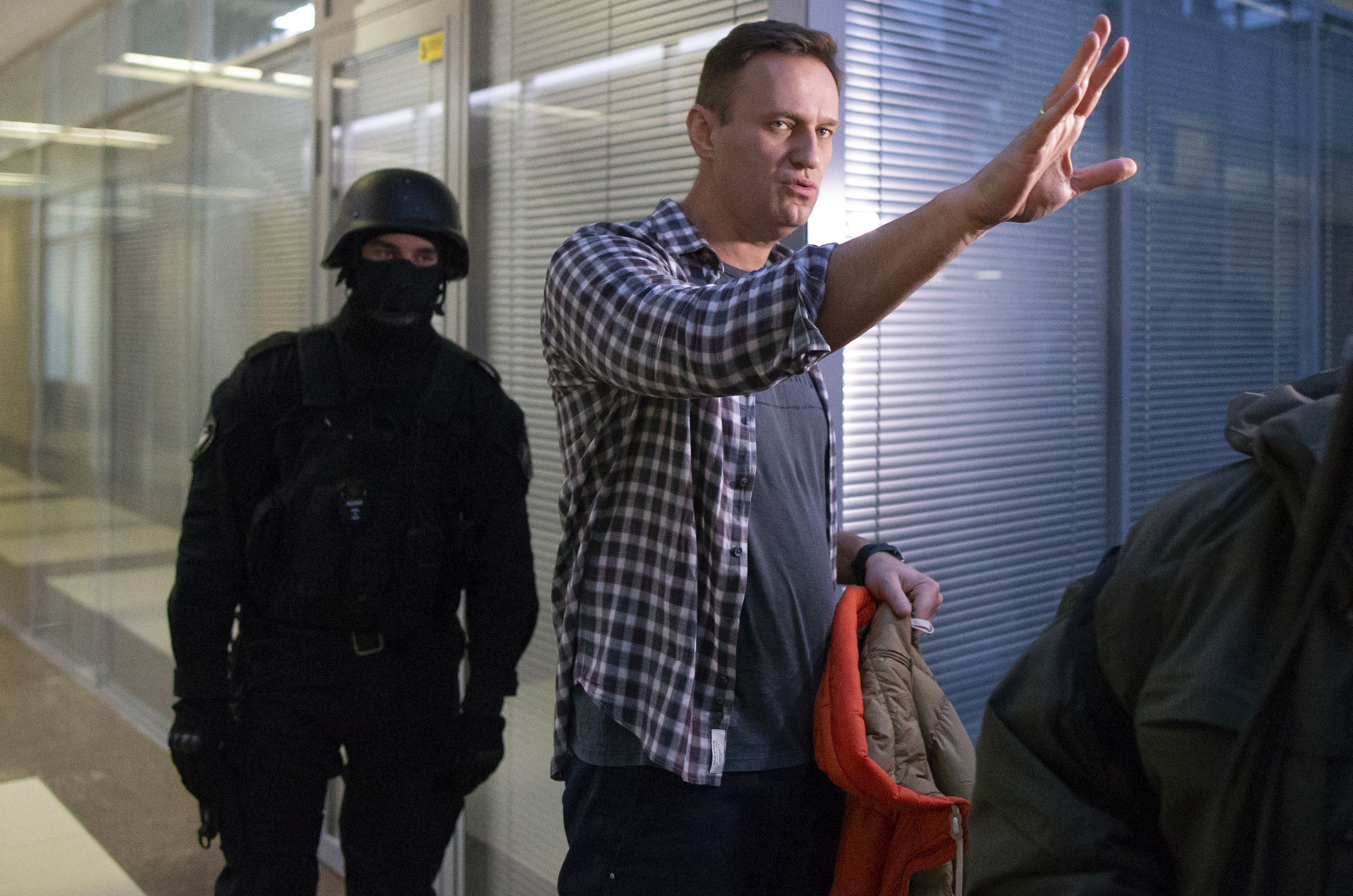 Russian opposition leader Alexei Navalny speaks to the media, flanked by a police officer, following his arrest. 