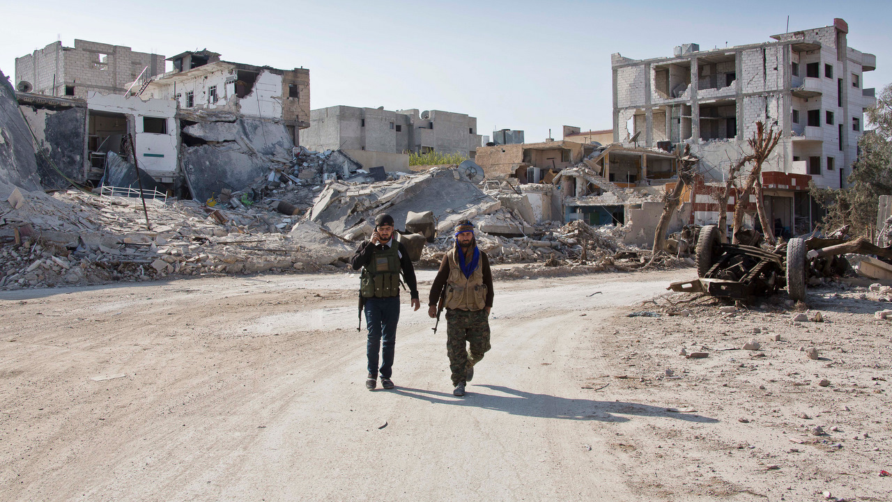 Kurdish People's Protection Units (YPG) soldiers walk near the town entrance circle heading to their strongholds in Kobani, Syria in 2014.