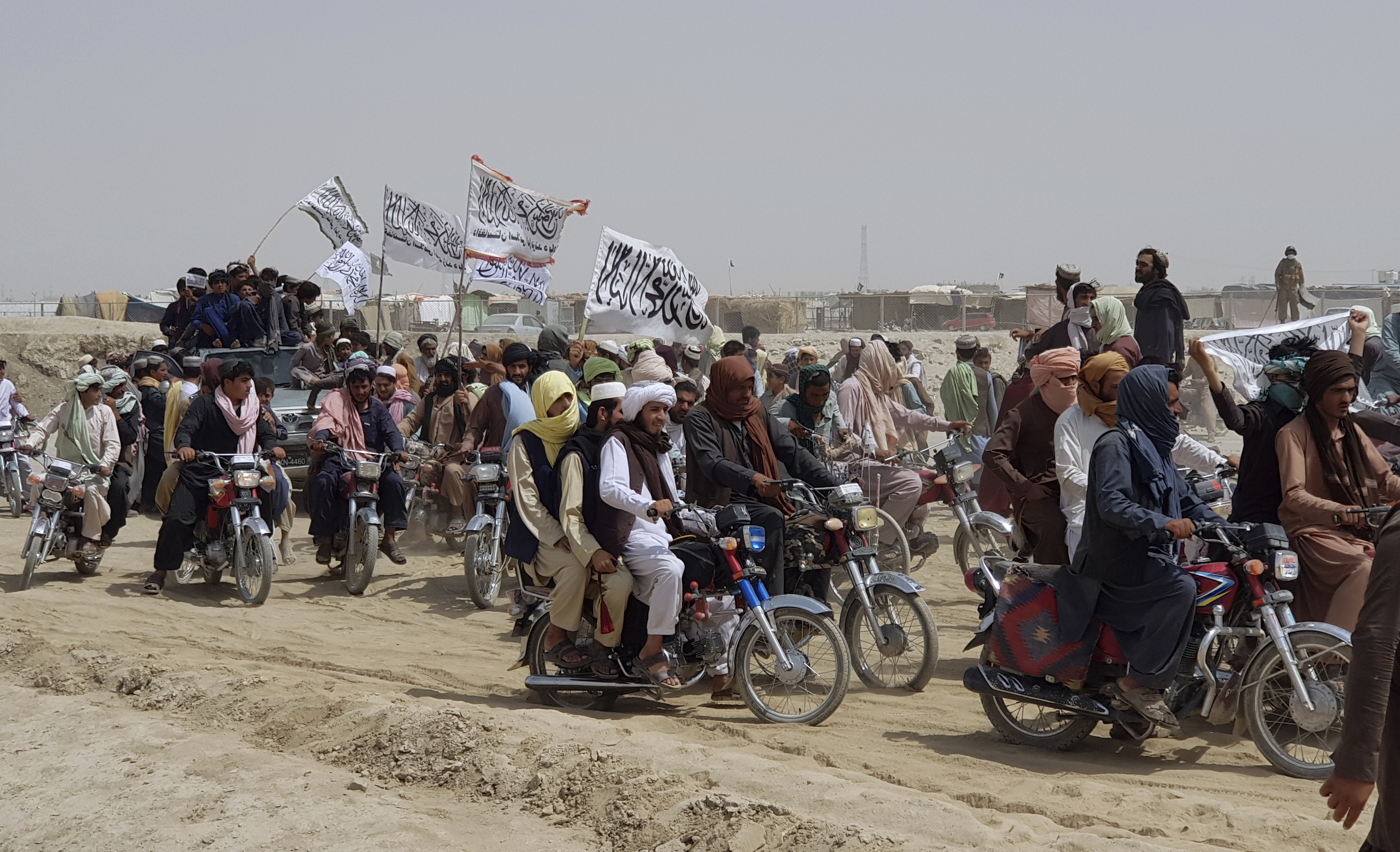 Supporters of the Taliban carry the Taliban's signature white flags in the Afghan-Pakistan border town of Chaman, Pakistan, Wednesday, July 14, 2021.