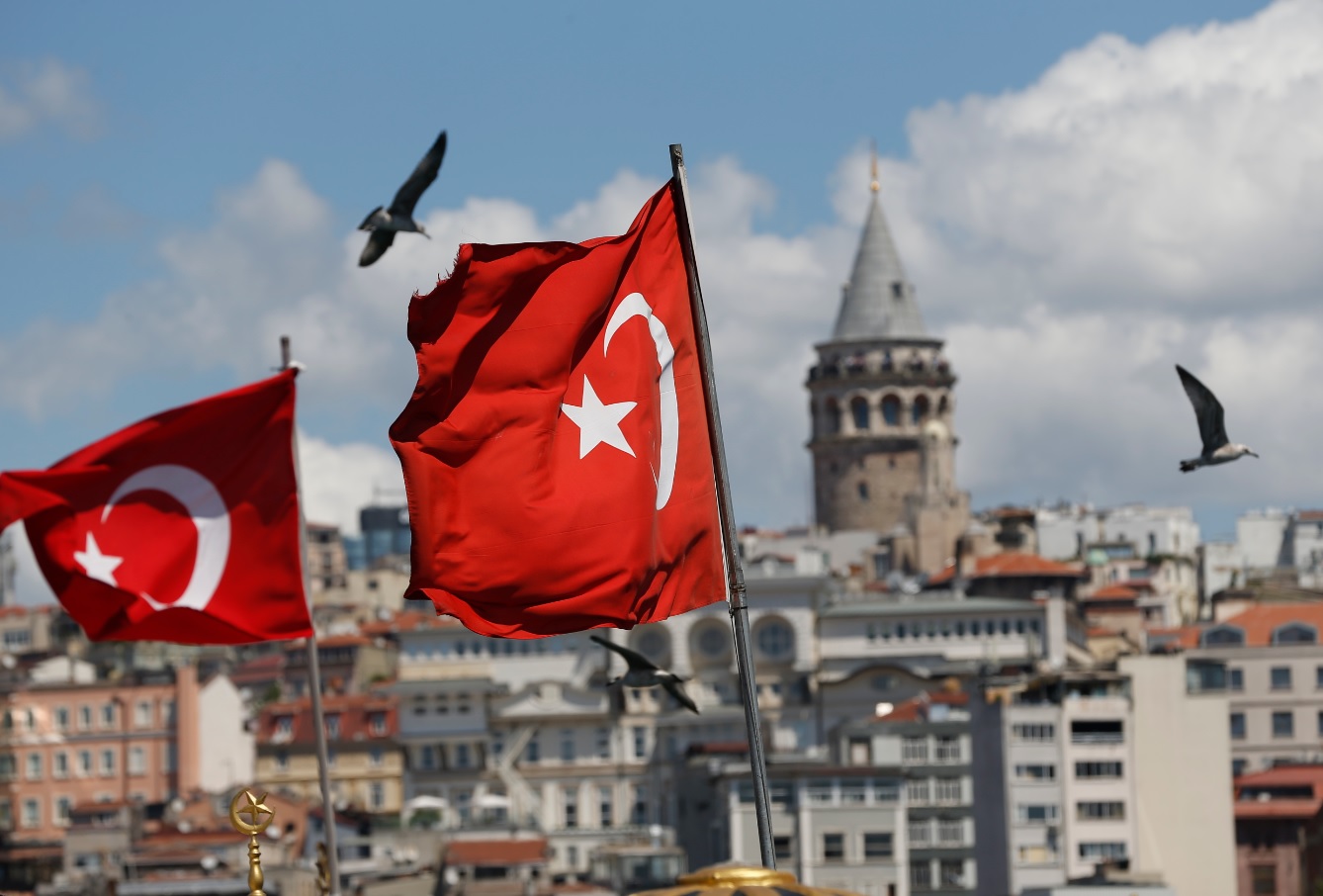 Backdropped by the iconic Galata Tower seagulls fly past Turkish flags in Istanbul, Monday, Aug. 13, 2018.