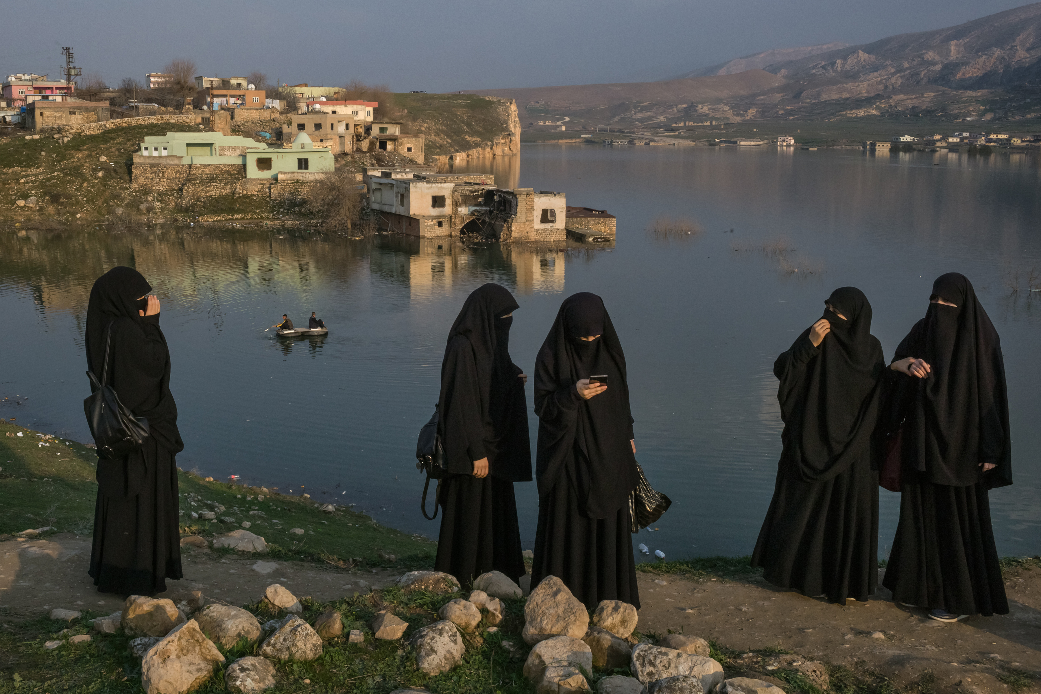 Visitors walk along the bank of the Tigris River as its rising waters flood the old town of Hasankeyf, Turkey, Feb. 24, 2020. 