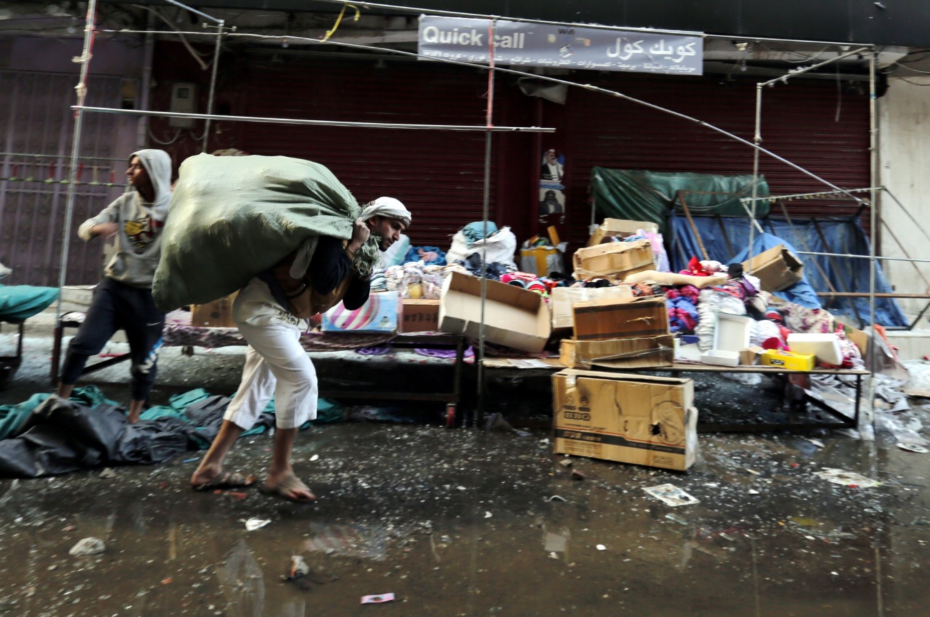 A Yemeni vendor carries belongings from a damaged mall near the residence of Yemeni ex-president Ali Abdullah Saleh (AAP)