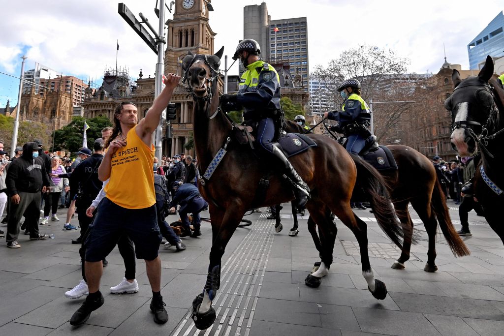 A protester (L) tries to push away a police horse in Sydney on July 24, 2021, as thousands of people gathered to demonstrate against the city's month-long stay-at-home orders. (Photo by Steven SAPHORE / AFP) (Photo by STEVEN SAPHORE/AFP via Getty Images)