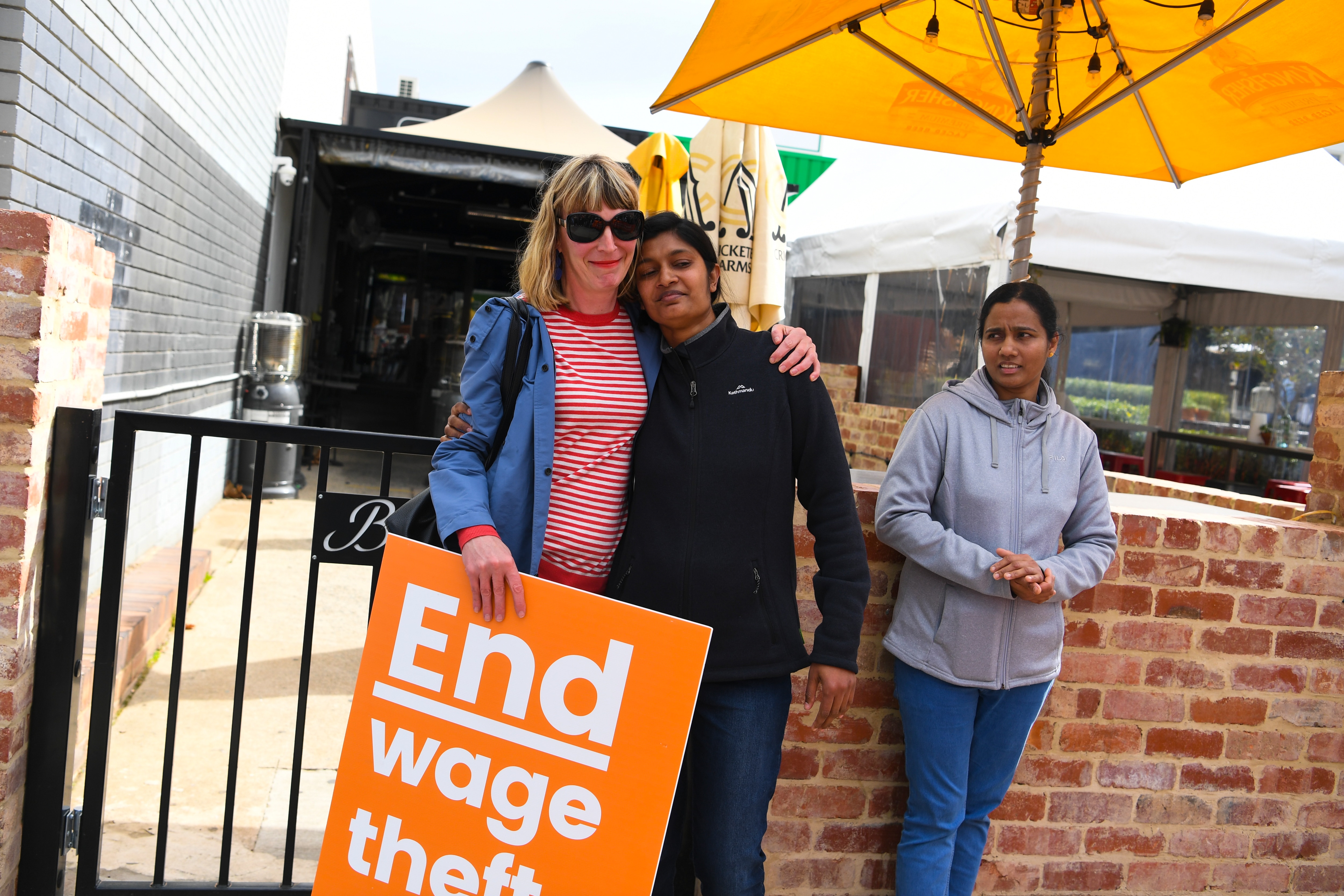 Former employees Shojin Thomas (centre) and Ninumol Abraham are seen near the Indian Restaurant Binny's Kathitto in Canberra.