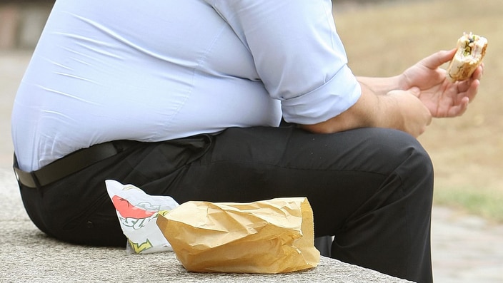 An overweight man eating his lunch