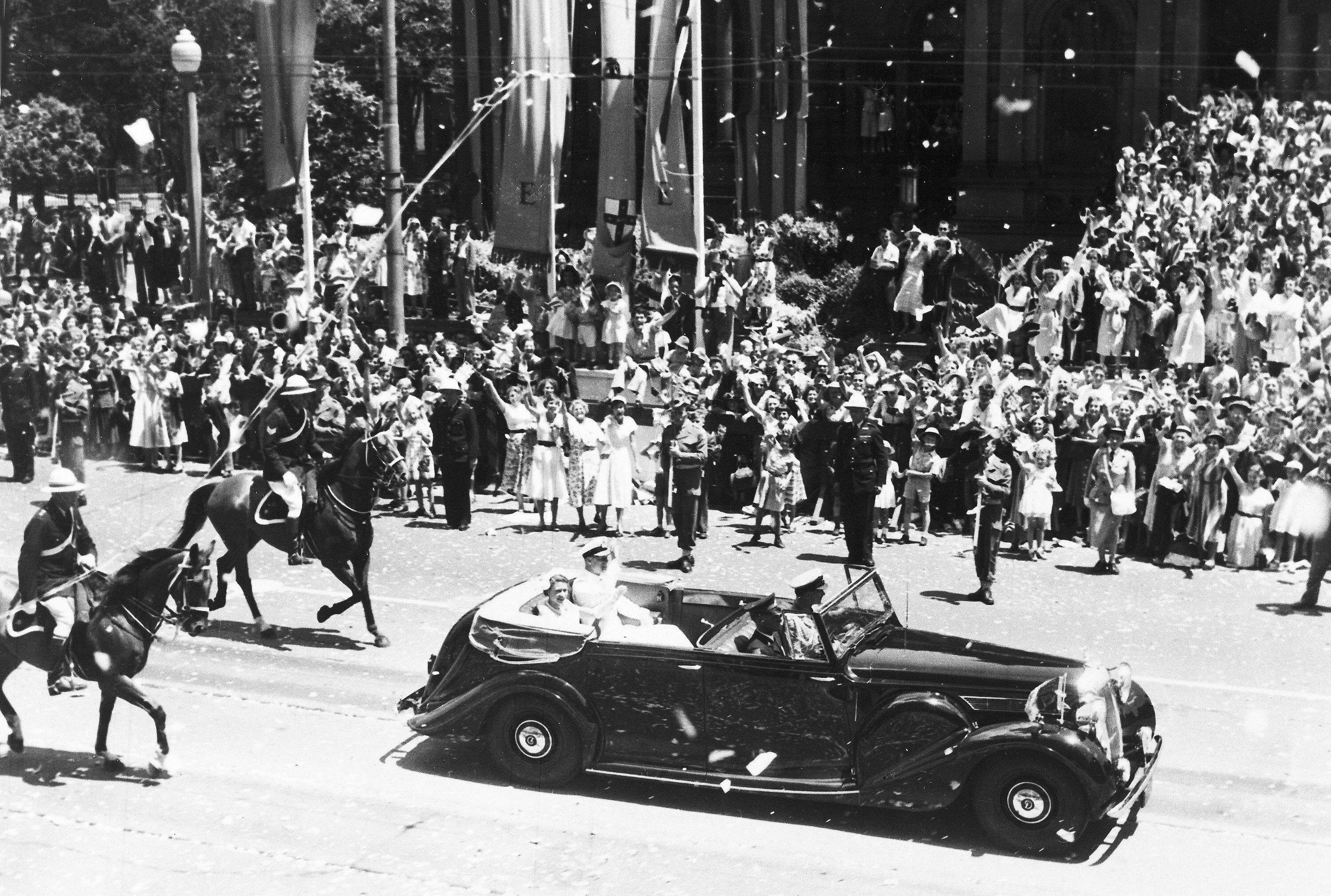 Queen Elizabeth II and Prince Philip in the back of a car driven in front of big crowds in Sydney in 1954.