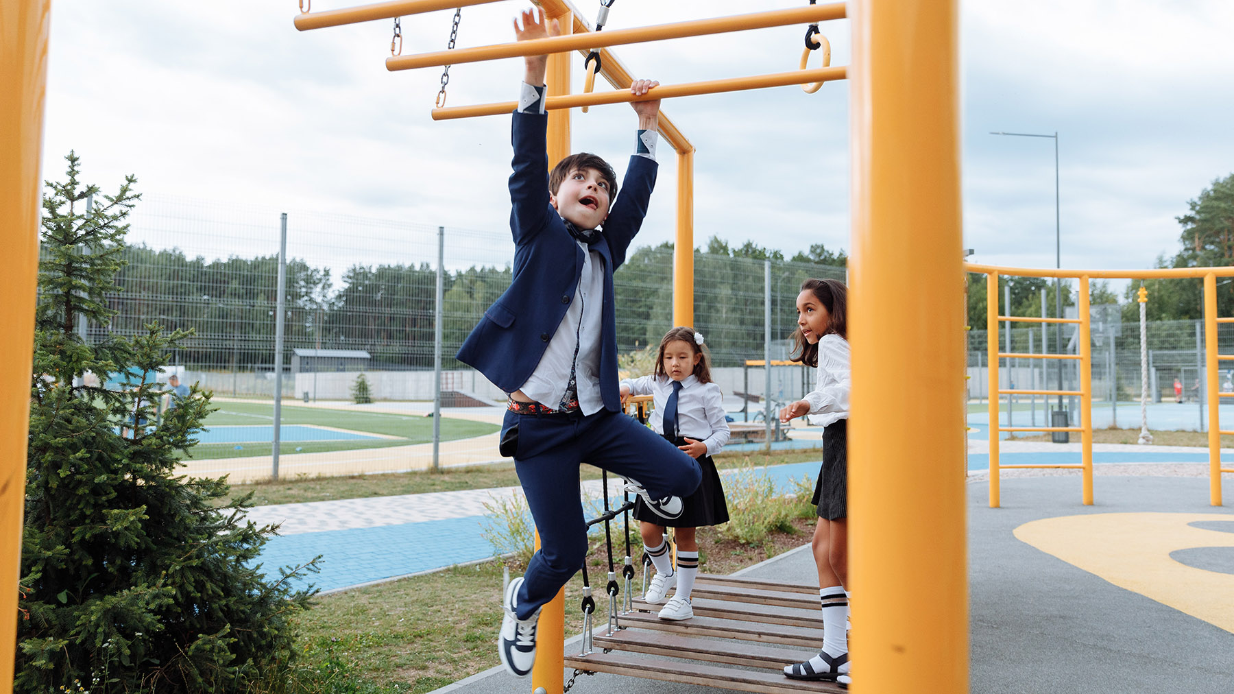 Boy hanging on Monkey Bars at school.