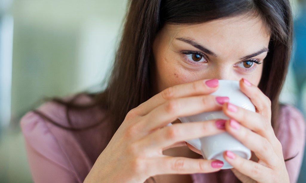 Young businesswoman having coffee in office