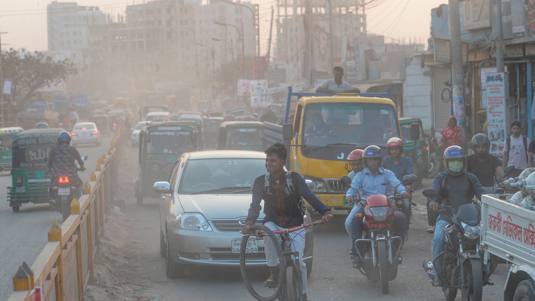 Commuters drive and ride on a road under heavy smog conditions in Dhaka on November 26, 2019. 