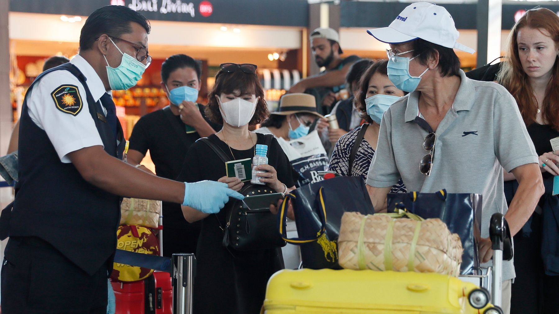 Passengers wearing protective masks walk at Ngurah Rai International Airport in Bali, Indonesia.