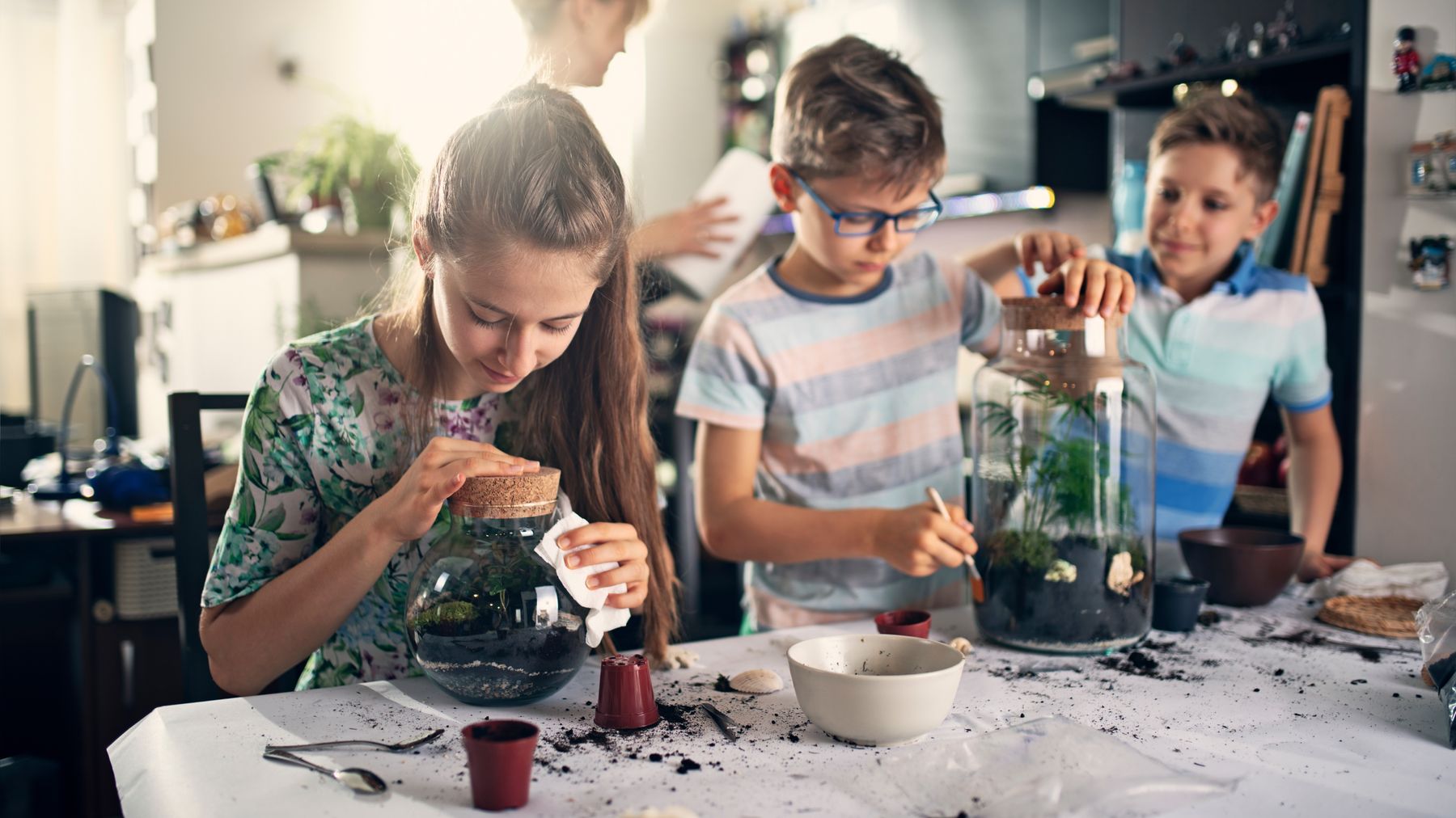 Kids having fun creating bottle gardens at home. 