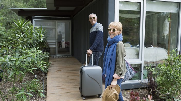 Portrait mature couple with suitcases arriving at vacation rental