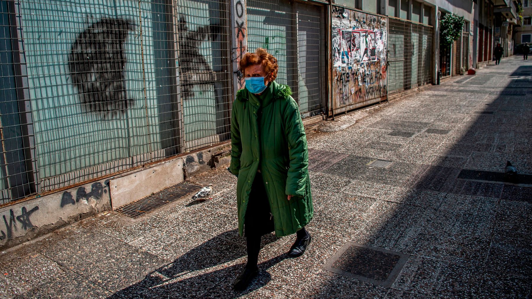 A woman wearing a protective mask walks in the centre of Athens