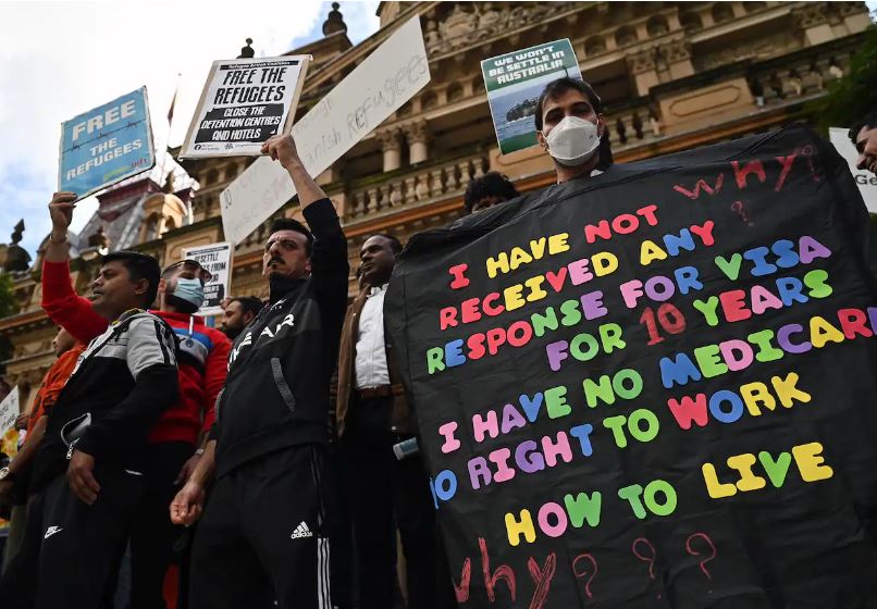 Protesters hold placards during a rally for refugee rights at Sydney Town Hall in Sydney, Sunday, 24 July 2022