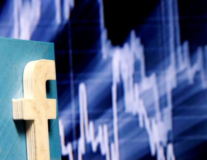 A 3D-printed Facebook logo is seen in front of a displayed stock graph in this illustration taken